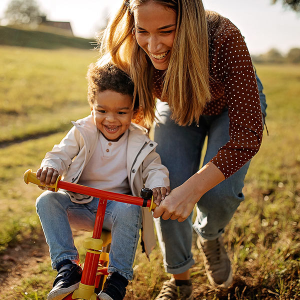 mom teaching kid how to ride bicycle